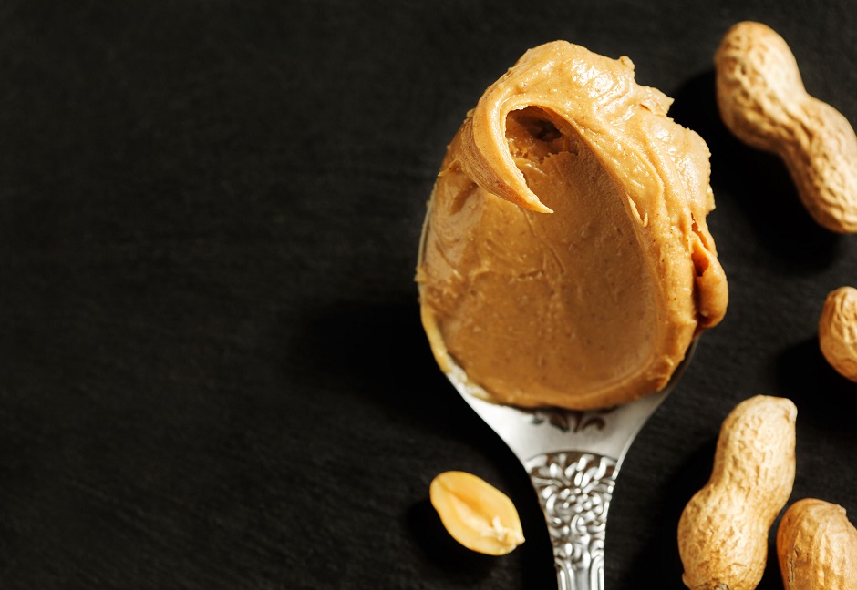 47935494 - peanut butter in spoon over black background